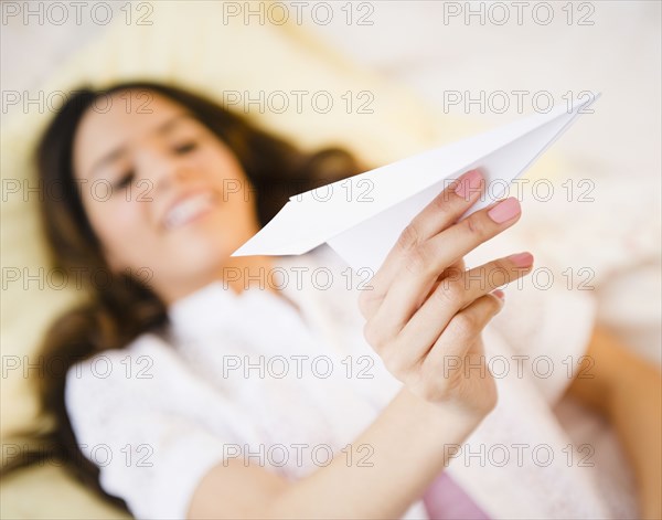 Hispanic woman holding paper airplane