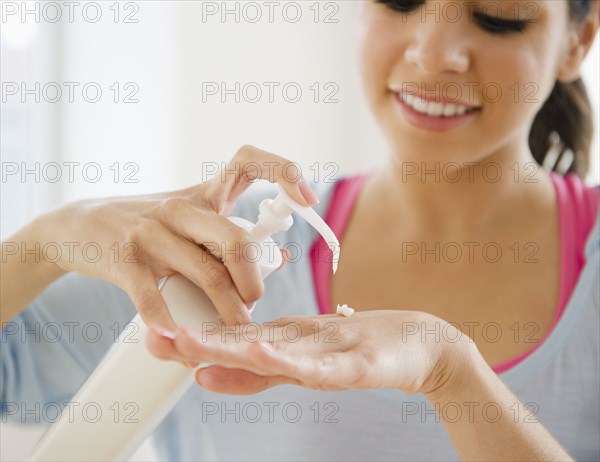 Hispanic woman putting on hand lotion