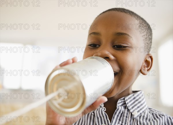 Black boy talking into tin can phone