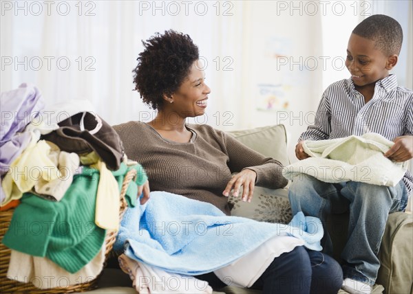 Black mother and son folding laundry