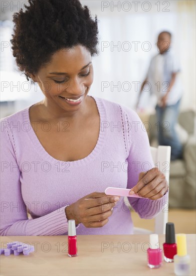 Black woman giving herself a manicure
