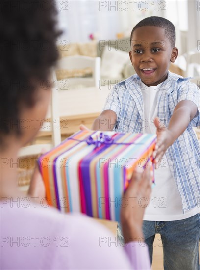 Black son handing mother a gift