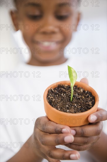 Black boy holding seedling in pot