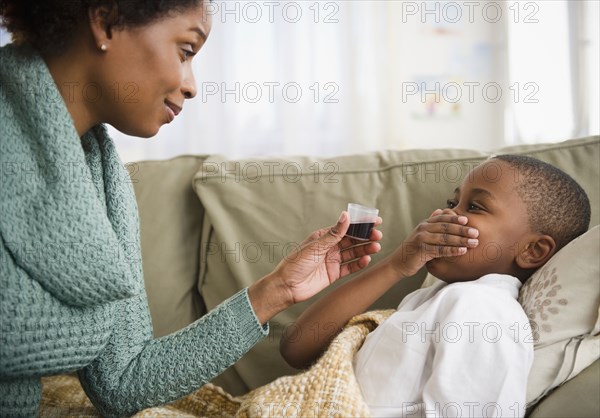 Black mother giving son cough syrup