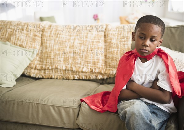 Pouting black boy in superhero cape