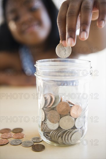 Black girl putting coins into a jar