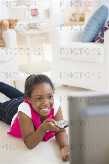 Black girl laying on floor watching television