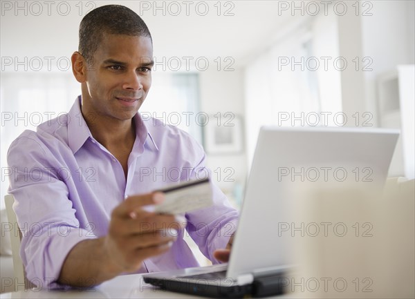 Mixed race man shopping online with credit card