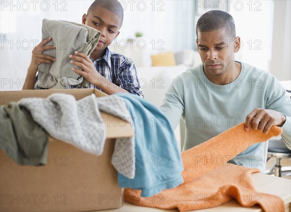 Father and son folding clothes for charity