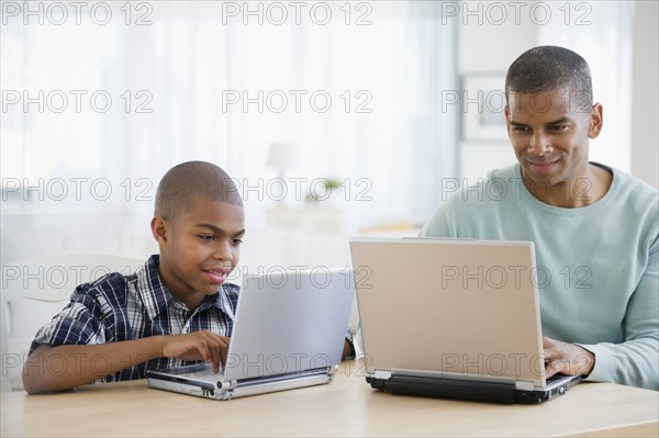 Father and son using laptops together