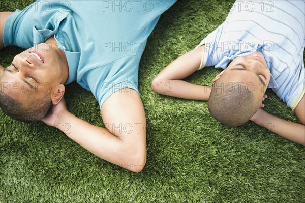 Father and son laying in the grass