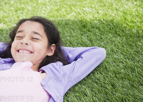 Mixed race girl laying in grass