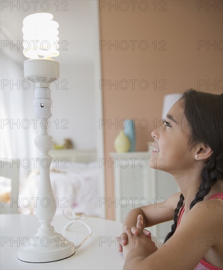 Mixed race girl looking at CFL light bulb