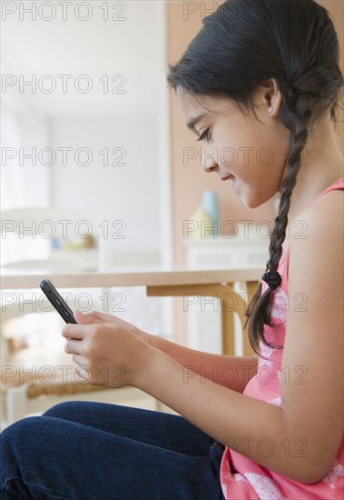 Mixed race girl text messaging on cell phone