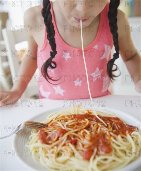 Mixed race girl eating spaghetti