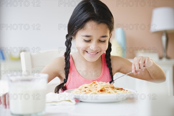 Mixed race girl eating spaghetti