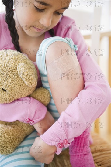 Mixed race girl looking at bandage on knee