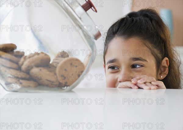 Mixed race girl looking at cookies in cookie jar