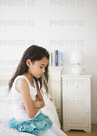 Mixed race girl sitting on bed