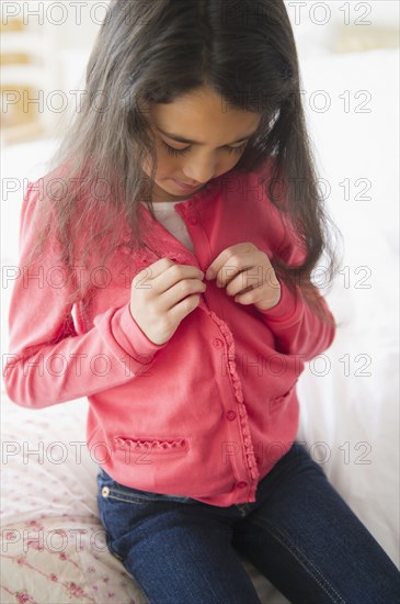 Mixed race girl buttoning her shirt