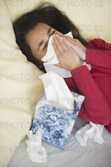 Mixed race girl blowing her nose