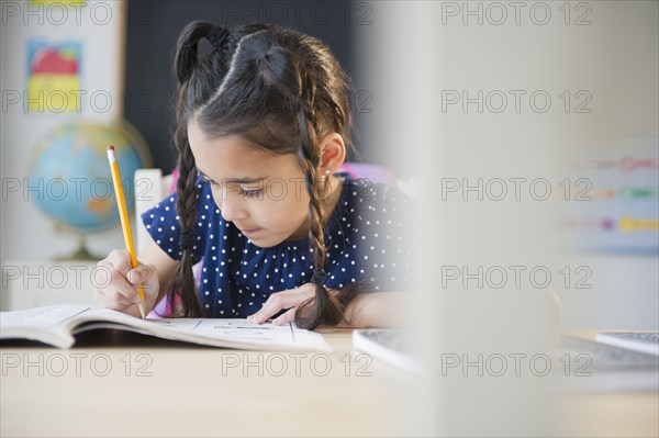 Mixed race girl writing in school