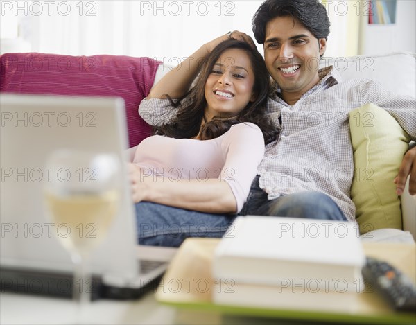 Mixed race couple watching television on laptop
