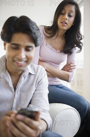 Mixed race woman watching husband text messaging