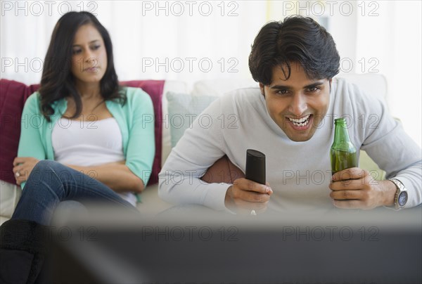 Angry girlfriend watching husband enjoy television