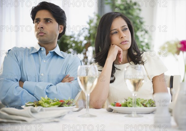 Unhappy mixed race couple dining together