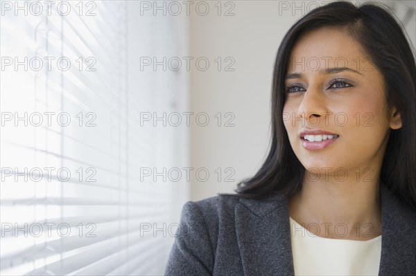 Mixed race businesswoman looking out window