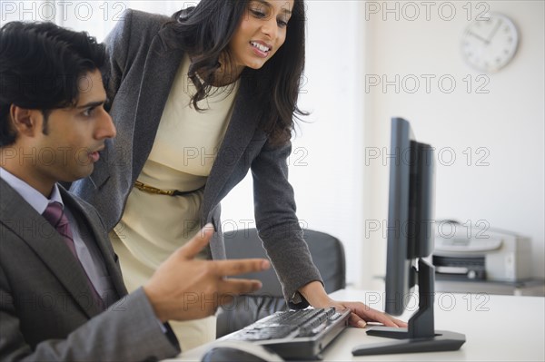 Mixed race business people looking at computer