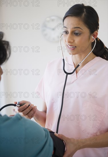 Mixed race nurse taking patient's blood pressure