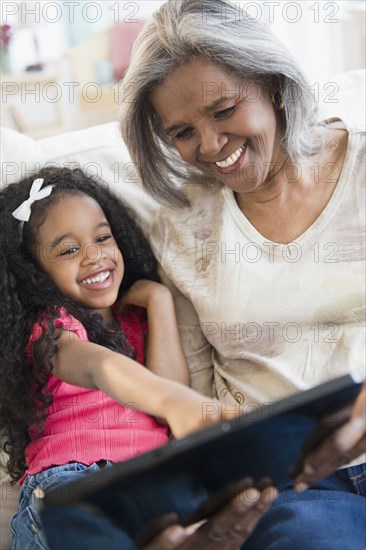 African American grandmother and granddaughter looking at digital tablet