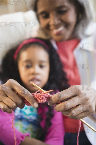 African American woman showing granddaughter how to knit