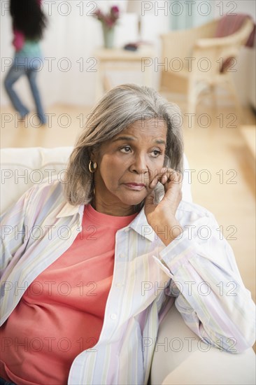 Serious African American woman sitting on sofa