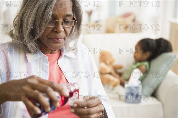 African American woman pouring cough syrup for granddaughter