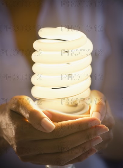 Cape Verdean woman holding CFL light bulb