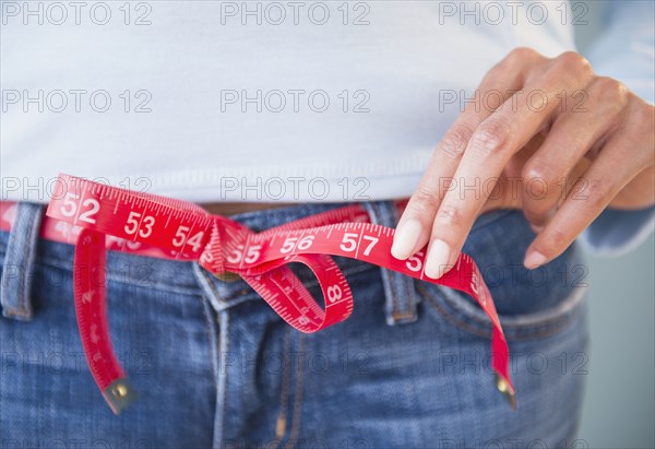 Cape Verdean woman using tape measure as belt