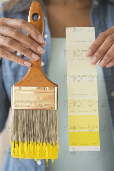 Cape Verdean woman holding color swatch and paintbrush