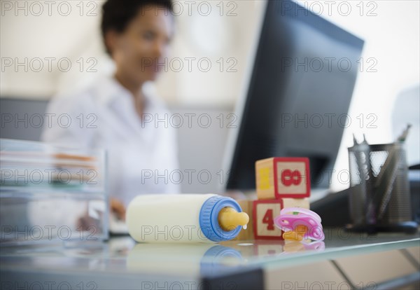 Baby bottle and blocks on African American woman's desk