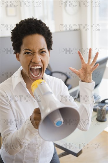 African American businesswoman using bullhorn in office