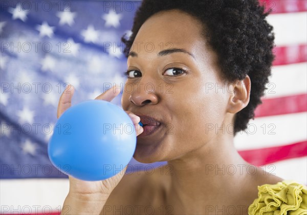 African American woman blowing up blue balloon