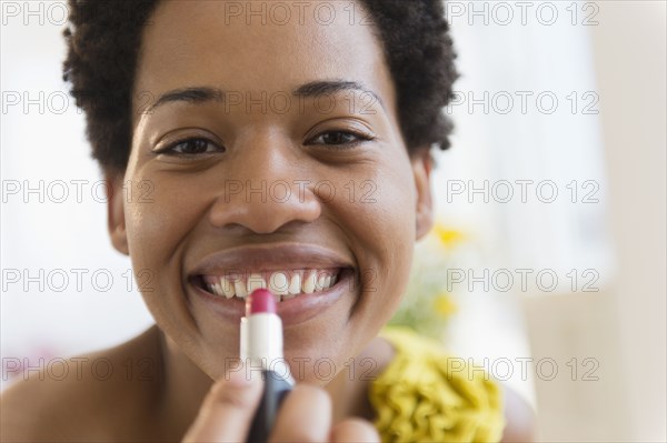 African American woman putting on lipstick