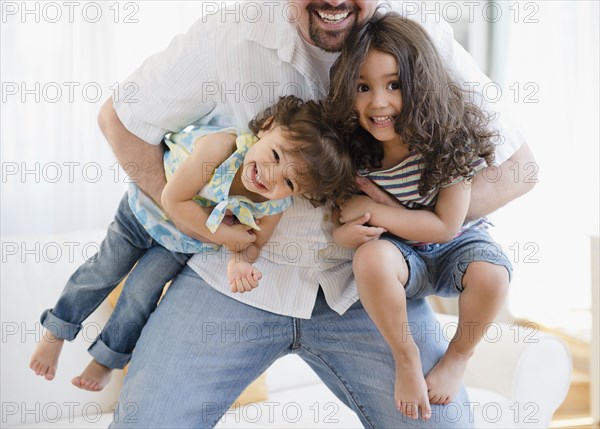Playful father carrying daughters