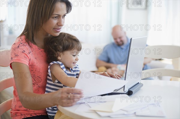 Mother working at computer with child on her lap