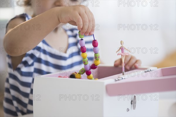 Mixed race girl taking jewelry from jewelry box