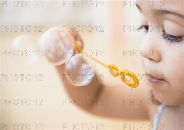Mixed race girl blowing bubbles