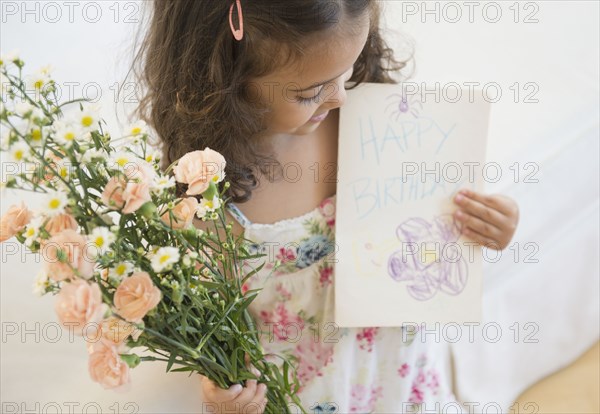 Mixed race girl holding flowers and birthday card