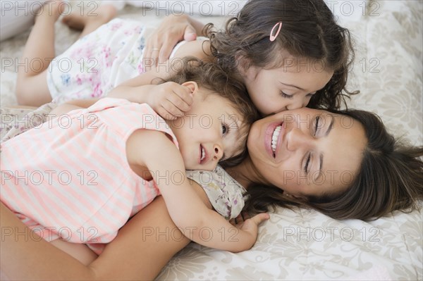 Mother and daughters laying on bed